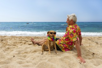 Relaxing elderly man with dog laying at the beach
