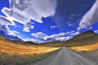 Patagonia. A dirt road in the Chile National Park Torres del Paine. Magic clouds incredible shapes
