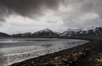 Icelandic dramatic landscape with frozen lake and mountains covered in snow in Iceland