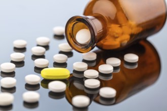 Many tablets with a glass container. Symbolic photo for addiction and costs in medicine and