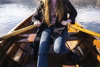 Young woman using paddle on a wooden boat, Lake Bled Slovenia rowing on wooden boats on a sunny day