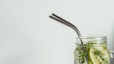 Cold drink in mason jar with metal straw on white background. Lemonade or detox water with lime and