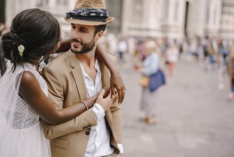 African-American bride hugs from behind a Caucasian groom. Interracial wedding couple. Wedding in