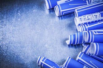 Composition of blue rolled construction drawings on metallic background maintenance concept