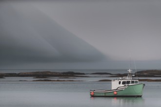 A commercial fishing boat sits tied to its mooring with dramatic clouds above, behind it are shoals