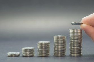 Great concept of savings, economy. Hand adding coin into pile of coins