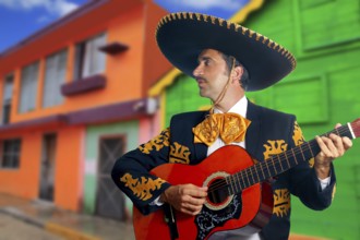 Charro Mariachi singer playing guitar in Mexico houses background
