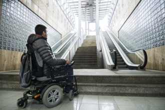 Rear View Of A Disabled Man On Wheelchair In Front Of Staircase