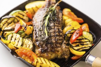 Beef steak with grilled vegetables in skillet