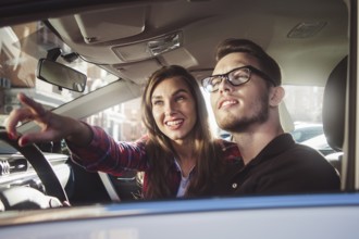 Enjoying travel. Beautiful young couple sitting on the front passenger seats and smiling while