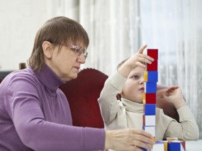 Granny is playing blocks with her grandson at home, Belgium, Europe