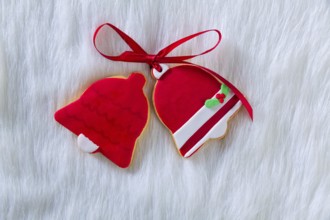 Christmas cookies Xmas red bell shape and ribbon on white fur background