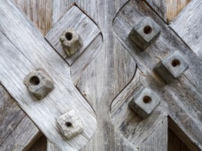 Weathered wooden planks intersecting with decorative square pegs showcasing traditional joinery