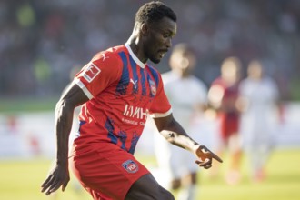 Football match, Sinlord CONTEH 1. FC Heidenheim looking down at the ball and pointing downwards,