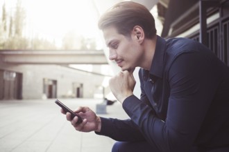 Smiling businessman use a smartphone at street