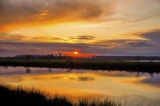 Sunset over a river with dramatic clouds and vivid reflection, Hunte 27798 Hude-Germany