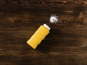 Spilled baby talcum powder on dark wooden background. Flat lay