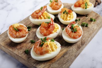 Boiled eggs stuffed with yolk and seasoned with mayonnaise, stuffed eggs with shrimp, on a wooden