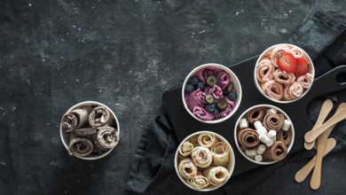 Rolled ice cream in cone cups on dark background. Different iced rolls top view or flat lay. Thai
