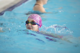 Child athlete swims in the pool. Swimming section