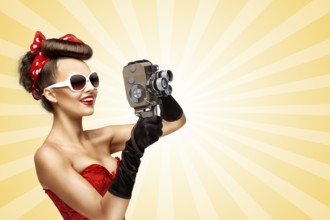 Glamorous pin up girl shooting a film with an old retro cinema 8mm camera on a colourful abstract