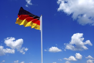 The flag of Germany flutters in the wind in a blue sky with white clouds