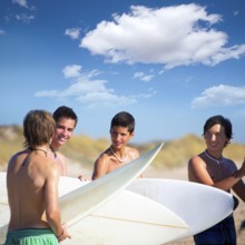 Surfer teen boys talking on beach shore holding surfboards