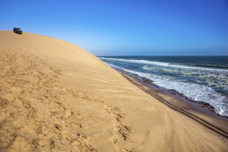 Ocean surf with foamy waves. Atlantic coast of Walvis Bay, Namibia, south of Africa. Dangerous jeep