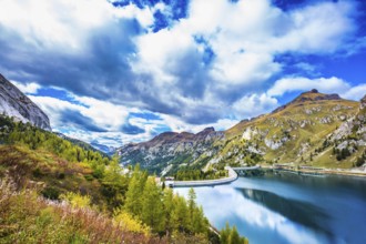 Grandiose glacial lake Lago di Fedaia in the Dolomites. Cloudy cold autumn day. The concept of