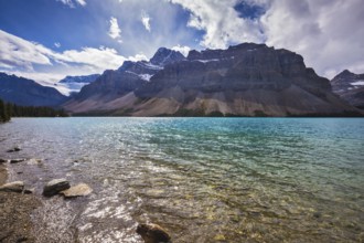 The cold waters of the lake surrounded by scenic Canadian Rocky Mountains. Azure Bow Lake in Banff