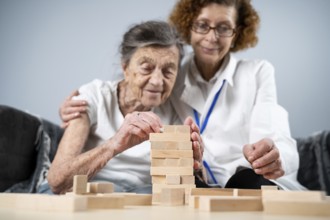 Senior woman practice skills, build wooden blocks, build tower and try not to let it fall, Jenga