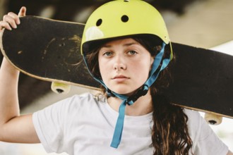 Schoolgirl after lessons at skateboarding practice in outdoor skate park. Stylish and beautiful
