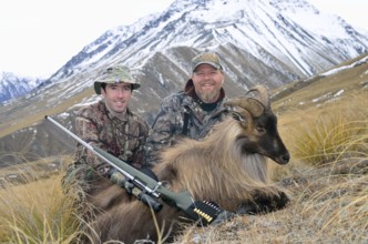 Hunters pose with their Himalayan tahr in the Southern Alps of New Zealand