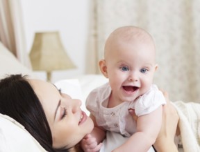 Happy smiling mother with six month old baby girl indoor