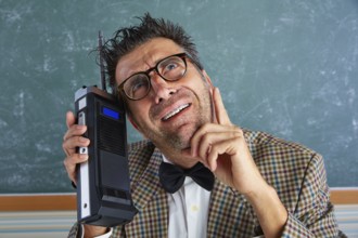 Nerd silly private investigator with retro walkie talkie on teacher balckboard