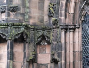 Details of ornately carved medieval stonework with niches and faces on the facade of chester