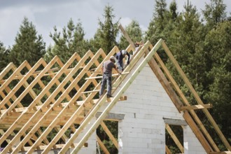 Two men work on the roof of house construction