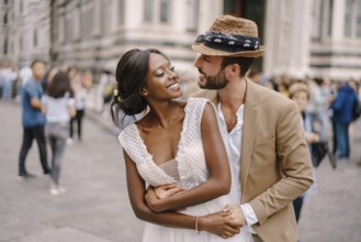 Wedding in Florence, Italy. Caucasian groom hugs from behind African-American bride at Piazza del