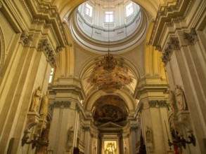 Impressive interior view of a baroque church with high columns and ornate frescoes on the ceiling,