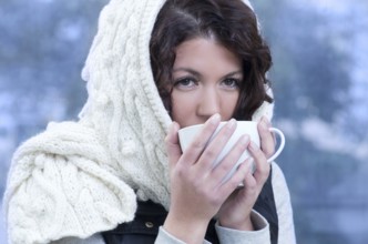 Pretty young caucasian brunette woman wearing white scarf with hood in a outdoor winter portrait