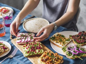 Female hands on dinning table. Young woman eat vegetarian toast. Vegan veggies sandwiches on