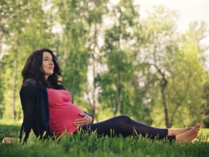Beautiful pregnant woman relaxing in park