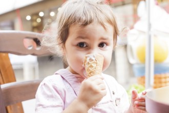 Loverly little girl eats an ice cream in cafe outdoor