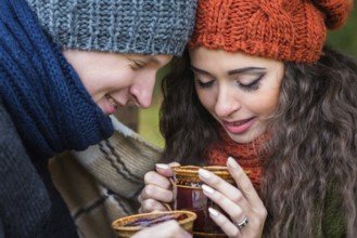 Young couple in love with a cup of coffee in the autumn garden