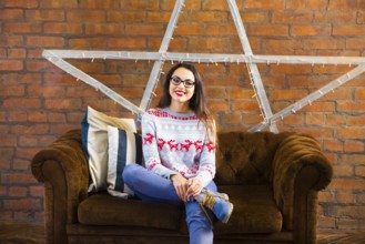 Pretty hipster girl sitting on couch at home in the living room