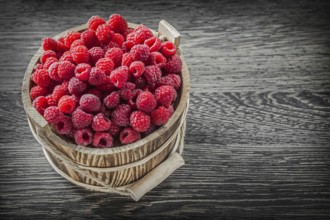 Red raspberry in bucket on vintage wooden board
