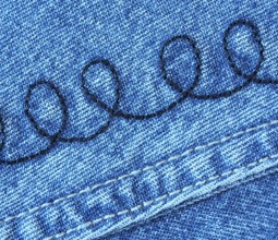 A detailed view of a piece of denim jeans fabric with a spiral pattern