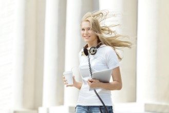 Beautiful young woman with vintage music headphones around her neck, holding a takeaway coffee and