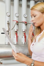 A young woman with a billing of heating costs for heating. In the boiler room. Austria