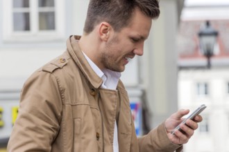 A man writes a text message on his mobile phone. Communication with a smart phone Austria